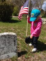 Child planting a flag next to a gravestone
